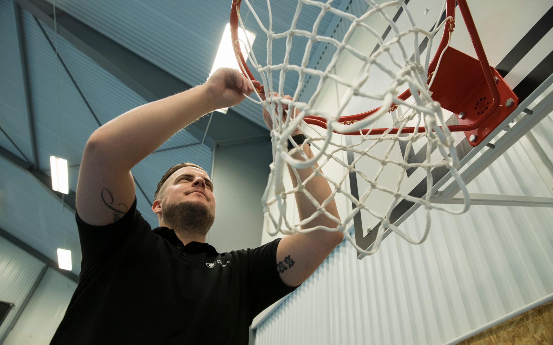 En anställd vid Farsta IP fixar med en basketkorg