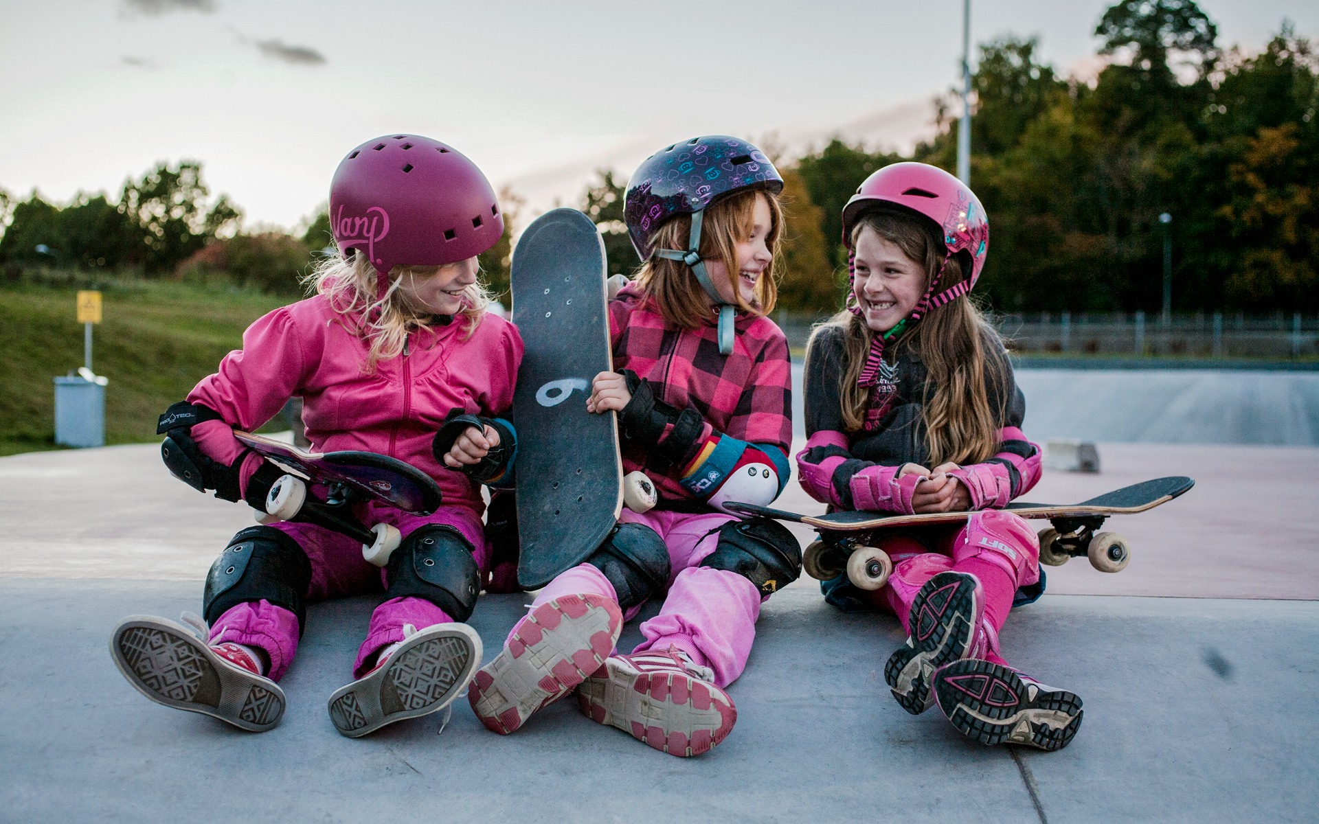 Tre glada tjejer sitter i en ramp i Skateparken i Högdalen